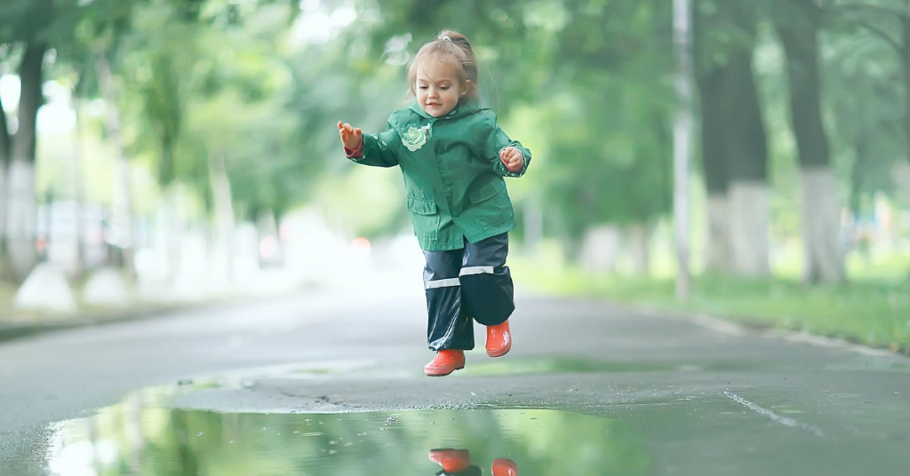 Bambino che salta in una pozzanghera